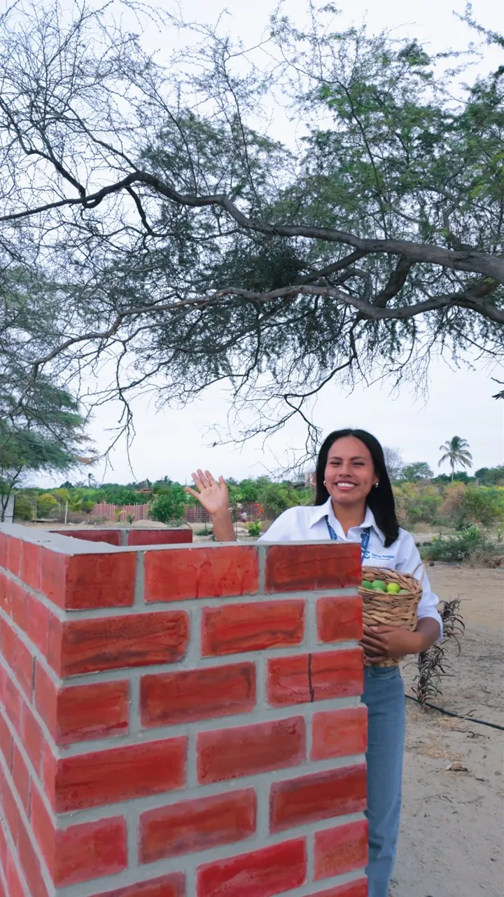 Asesora de Terra Hogar saludando junto a la parrilla de ladrillo del proyecto
